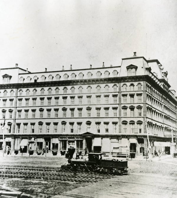 1875: A wood-burning locomotive engine rolls in front of the south facade of first Kimball House. Note the banks in Kimball House. In 1883, the hotel burned down in only four hours, and all 300 guests were evacuated safely. (AJC Archive at GSU Library   AJCP582-14l)