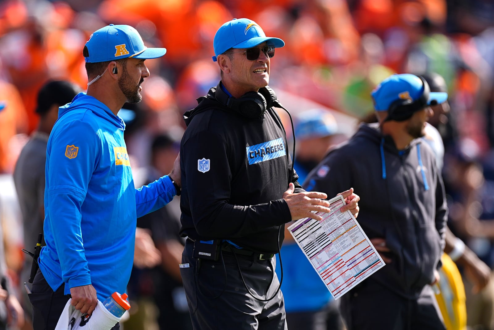 Los Angeles Chargers head coach Jim Harbaugh, center, stands on the sideline during the first half of an NFL football game against the Denver Broncos, Sunday, Oct. 13, 2024, in Denver. (AP Photo/David Zalubowski)