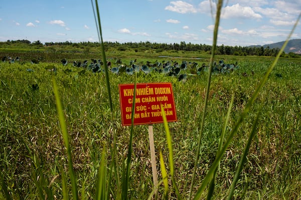 FILE- A warning sign stands in a field contaminated with dioxin near Danang airport, during a ceremony marking the start of a project to clean up dioxin left over from the Vietnam War, at a former U.S. military base in Danang, Vietnam, Aug. 9, 2012. The sign reads; "Dioxin contamination zone - livestock, poultry and fishery operations not permitted." (AP Photo/Maika Elan, File)