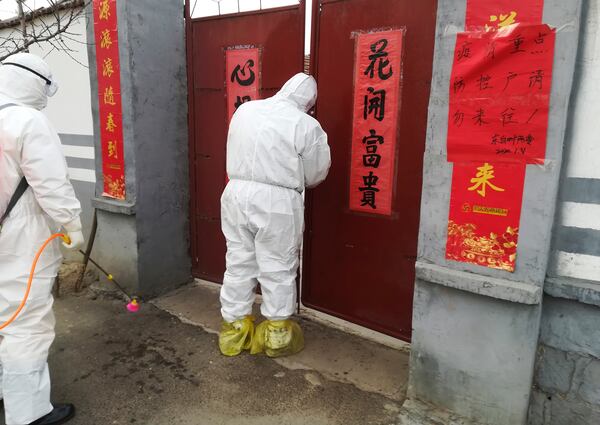 Government workers in protective suits visit a family under home quarantine in Zouping in eastern China's Shandong Province. 