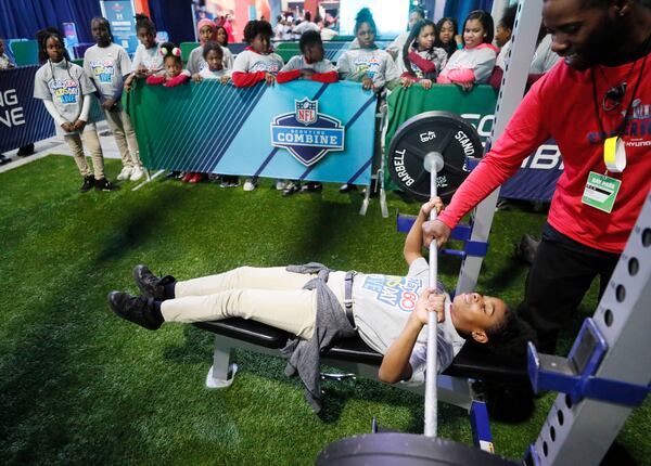 Erin Evans tries her hand at the bench press in the Scouting Combine attraction. NFL PLAY 60 Kids' Day gave more than 2,000 local youth to spend the day at the Super Bowl Experience.  The kids were free to roam through the many attractions at the Georgia World Congress Center. (Bob Andres / bandres@ajc.com)