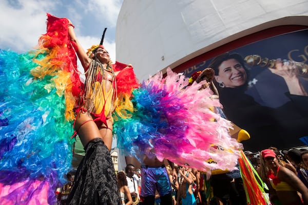 FILE - A reveler on stilts parades past a poster featuring Oscar-nominated actress Fernanda Torres, during the Caxias Water Planet pre-Carnival street party, in Duque de Caxias, Brazil, Feb. 9, 2025. (AP Photo/Bruna Prado, File)