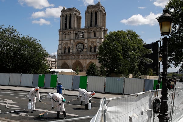 FILE - Workers wearing disposable underwear and other protective gear after a delay prompted by fears of lead contamination clean the area in front of Notre-Dame de Paris cathedral, on Aug. 19, 2019 in Paris. (AP Photo/Francois Mori, File)