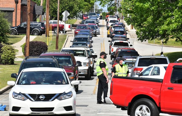 Police officers control traffic as motorists and their passengers wait to get tested at two drive-through COVID-19 testing sites at Good News Clinic in Gainesville on Tuesday, April 28, 2020. Northeast Georgia Health System partnered with Good News Clinic to test more than 300 Hall County adults and children for COVID-19. (Hyosub Shin / Hyosub.Shin@ajc.com)