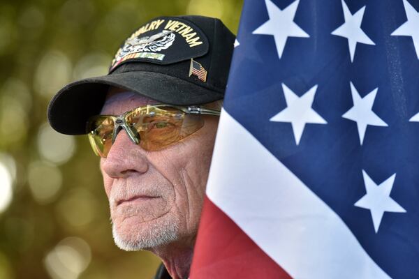 Patriot Guard Rider Thomas Buchanan holds an American flag as the group sets up a “flag line” before the funeral service for Kelvin Ansari, a Savannah police officer. HYOSUB SHIN / HSHIN@AJC.COM