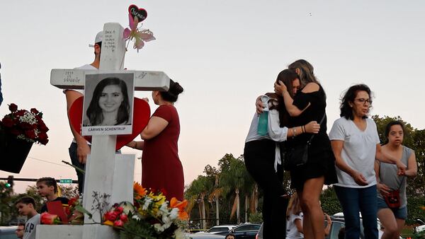 Magaly Newcomb, right comforts her daughter Haley Newcomb, 14, a student at Marjory Stoneman Douglas High School, at a makeshift memorial outside the school, in Parkland, Fla., Sunday, Feb. 18, 2018.  Nikolas Cruz, a 19-year-old who had been expelled from the school, is being held without bail in the Broward County Jail, accused of 17 counts of first-degree murder.  (AP Photo/Gerald Herbert)