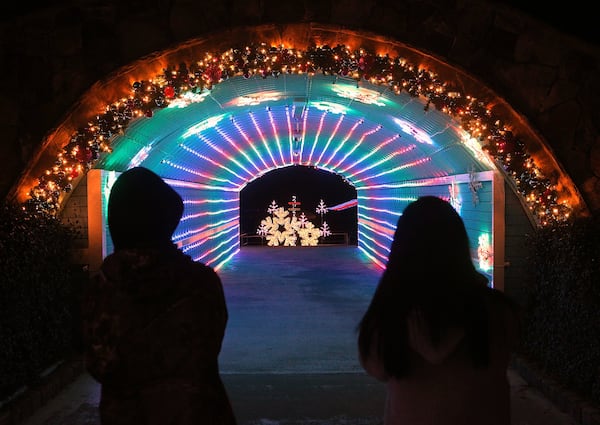 A pair of visitors take in the festive light display in a tunnel at Margaritaville in Lanier Islands in Buford. Curtis Compton/ccompton@ajc.com