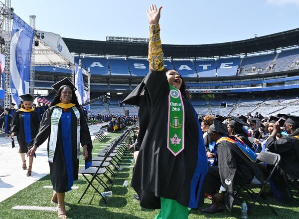 A graduate waves to family members and friends during Georgia State University's master’s degree commencement ceremony at Center Parc Stadium on Wednesday, May 4, 2022. (Hyosub Shin / Hyosub.Shin@ajc.com)