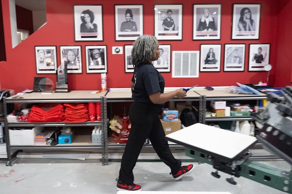 Cher’Don Reynolds, President and CEO of She Prints It, walks past her wall of inspirational female CEOs in her basement production studio in Lithonia on Monday, Dec. 23, 2024.  (Ben Gray for the Atlanta Journal-Constitution)