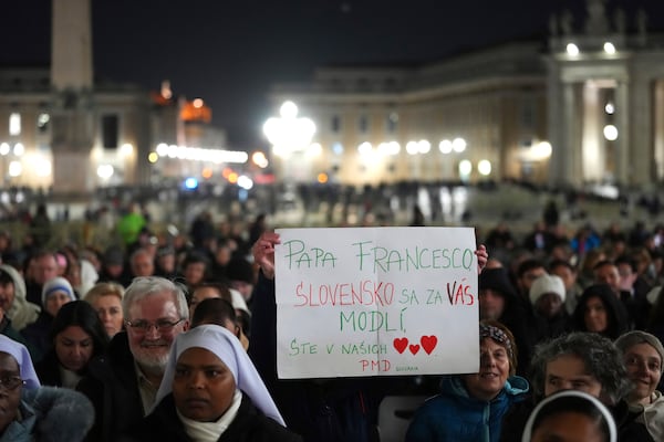 People hold up a banner before Cardinal Robert Francis Prevost, Prefect of the Dicastery for Bishops, leads the recitation of the Holy Rosary for Pope Francis' health in St Peter's Square at the Vatican, Monday, March 3, 2025. (AP Photo/Kirsty Wigglesworth)