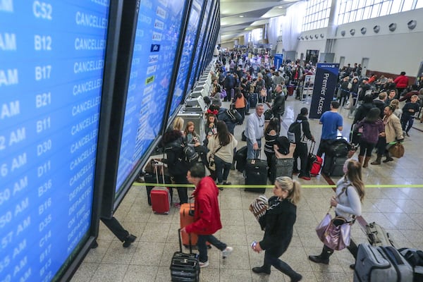 Travelers pass under the flight board showing cancellations in the North terminal on Monday Dec. 18, 2017, at Hartsfield-Jackson International Airport the day after a massive power outage brought operations to halt. JOHN SPINK/JSPINK@AJC.COM