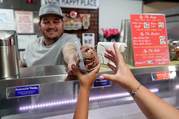 Johnny Wilson hands a young customer their chocolate ice cream at Happy Days Ice Cream Parlor in Guyton.