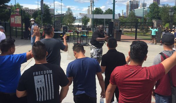 Evangelist Emill Bridges leads the group gathered outside Centennial Park in a roadside worship service.