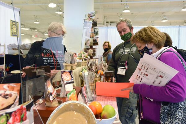 Shirley-Kaufman-Jones (left), president of Country Home Creations, helps buyers Tina and Jeff Salmans, who came to Atlanta Market from West Virginia to buy products for their gift shop. Atlanta's busy convention and event industry screeched to a halt last year because of the coronavirus. Organizers are hopeful the rollout of vaccines will bring business back to normal. Hyosub Shin / Hyosub.Shin@ajc.com)