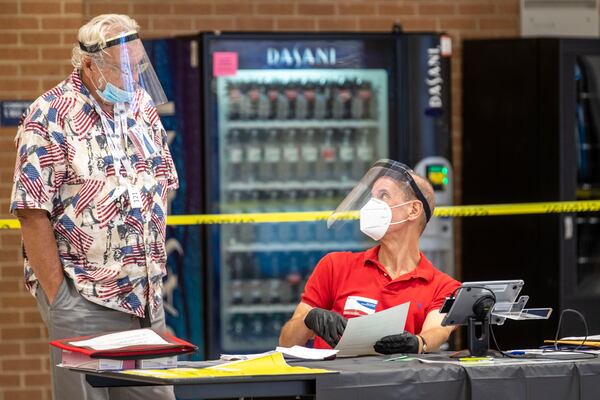 Gwinnett County poll manager Don Heaton, left, speaks with assistant poll manager Bob Portnoy during Georgia primary runoff elections Tuesday at Norcross High School. (ALYSSA POINTER / ALYSSA.POINTER@AJC.COM)