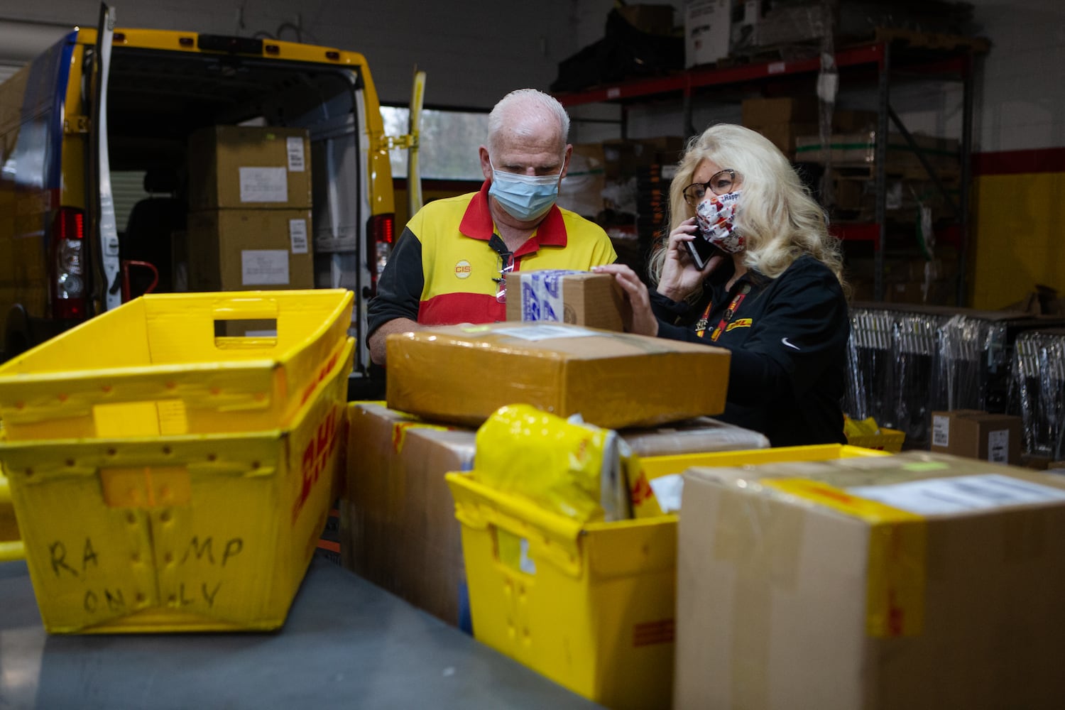 Tim Brothers checks boxes (left) while Lisa Miller (right) takes a phone call on Wednesday, December 16, 2020, at DHL Express in Atlanta. Workers at the shipping center worked to fulfill orders during the holiday rush. CHRISTINA MATACOTTA FOR THE ATLANTA JOURNAL-CONSTITUTION.