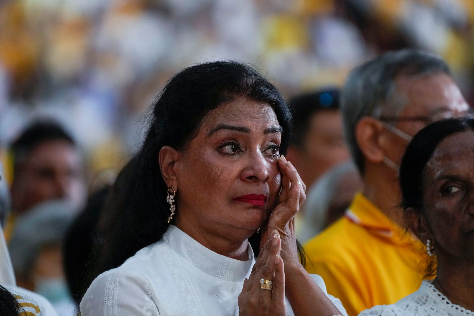 A woman gets emotional as Pope Francis presides over a mass 'In Memory of the Most Holy Name of Mary' celebrated by the Archbishop of Singapore, Cardinal William Goh Seng Chye at the Singapore SportsHub National Stadium, Thursday, Sept. 12, 2024. Pope Francis has praised Singapore's economic development as a testament to human ingenuity. But he's urging the city-state to look after the weakest too. Francis made the remarks Thursday on the final leg of the longest and farthest tour of his papacy. (AP Photo/Gregorio Borgia)