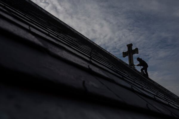 A roofer works on a church in Paris, Tuesday, Oct. 15, 2024. (AP Photo/Louise Delmotte)