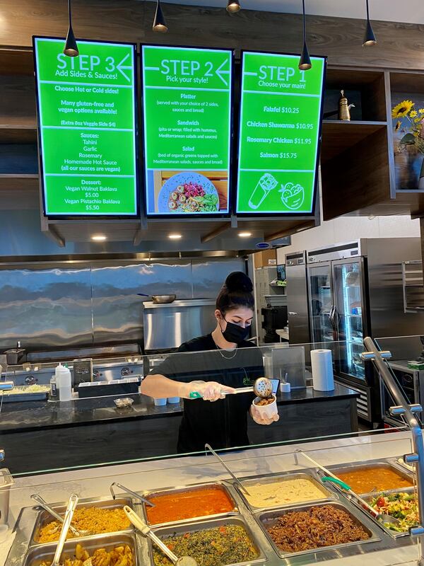 A server at Aviva by Kameel scoops up a to-go container of mujadarra, a dish of creamy lentils with fried onions. Wendell Brock for The Atlanta Journal-Constitution