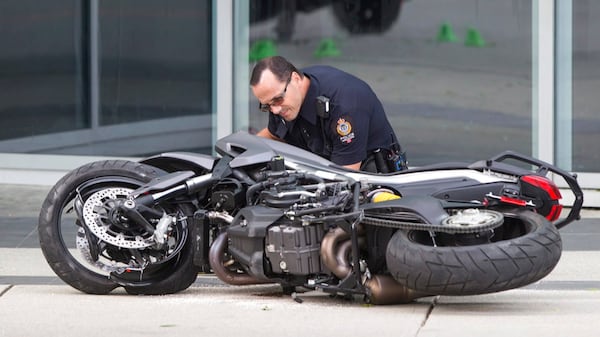 A police officer examines a motorcycle after a female stunt driver working on the movie "Deadpool 2" died after a crash on set, in Vancouver, B.C., on Monday Aug. 14, 2017. Vancouver police say the driver was on a motorcycle when the crash occurred on the movie set on Monday morning. (Darryl Dyck/The Canadian Press via AP)