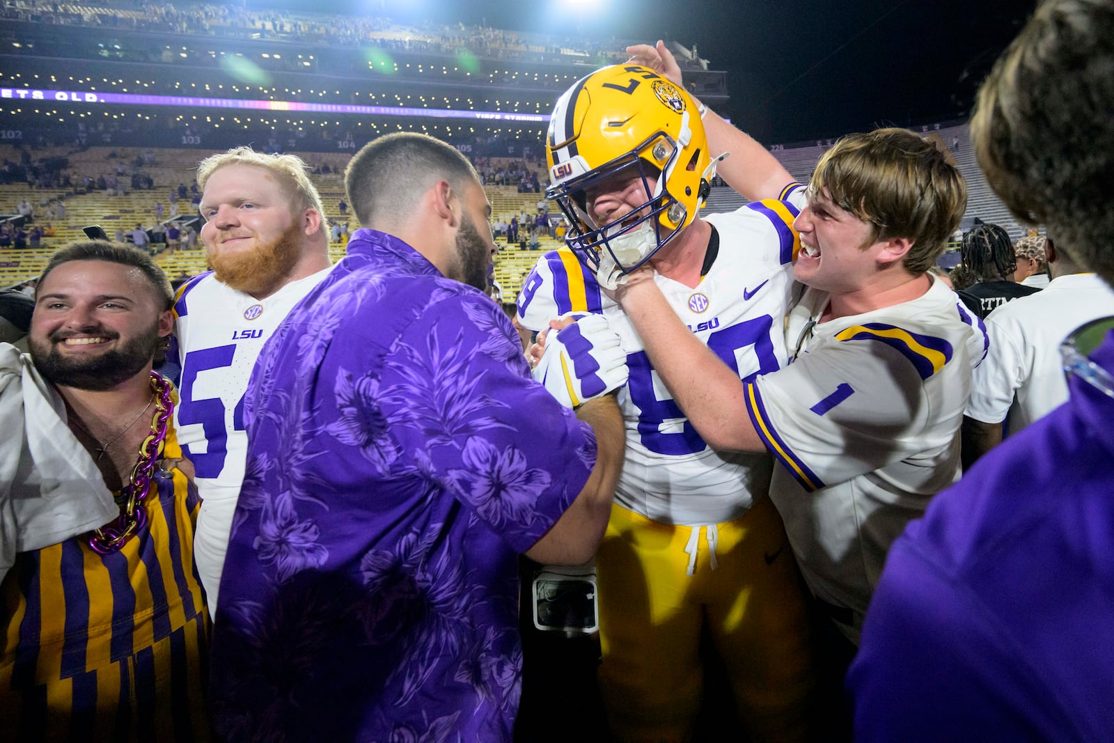 LSU offensive lineman Bo Bordelon (89) and LSU offensive lineman Aaron McDaniel (54) celebrate with LSU fans after they rushed the field after the team's overtime victory over Mississippi during an NCAA college football game in Baton Rouge, La., Saturday, Oct. 12, 2024. (AP Photo/Matthew Hinton)