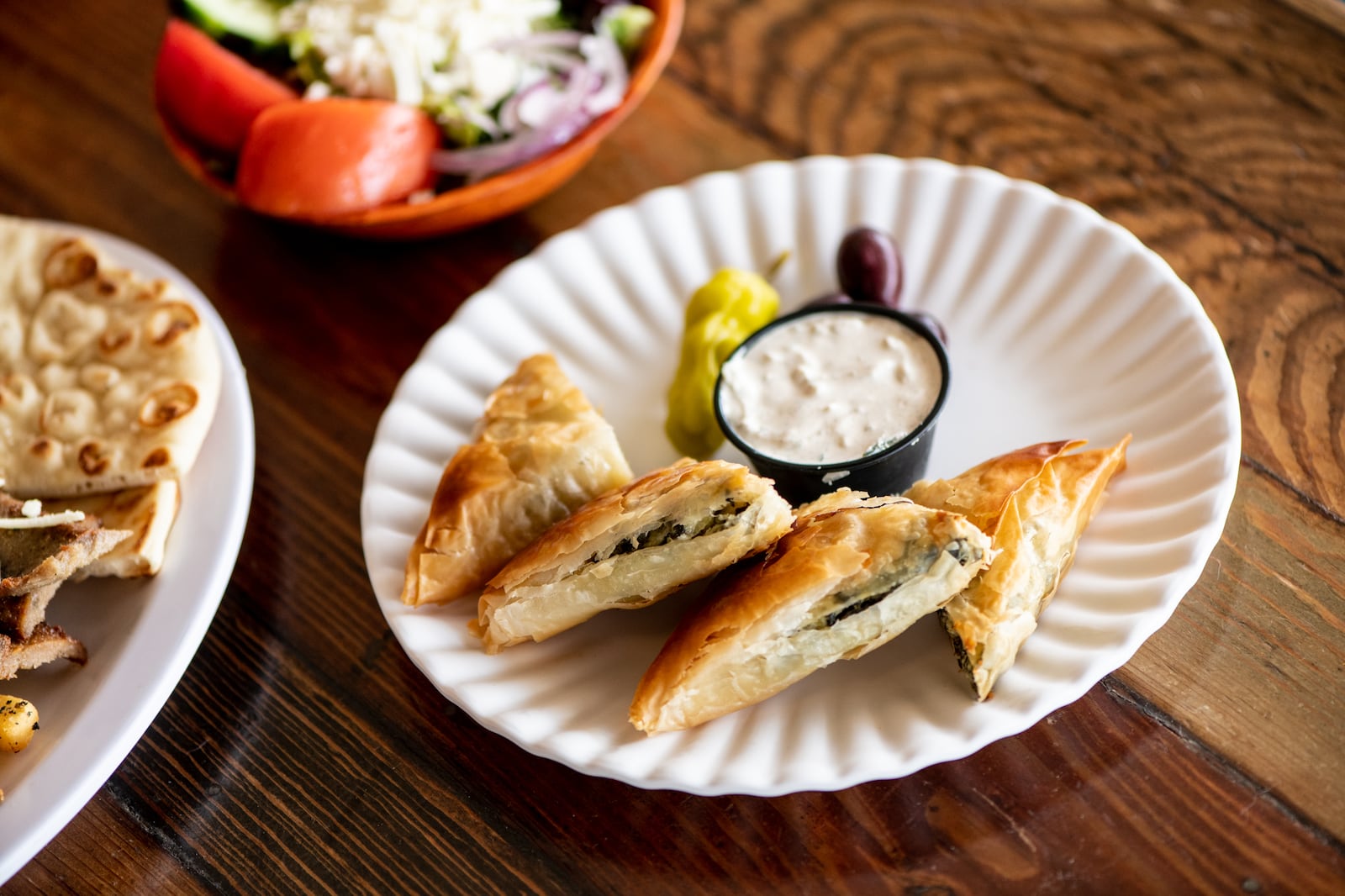 The Greek Pizzeria and Gyros Spanakopita with spinach, feta, phyllo pies, and side of tzatziki. (Mia Yakel for The Atlanta Journal-Constitution)