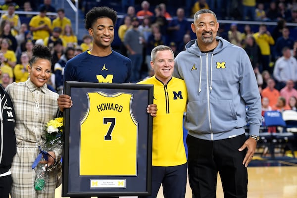 Michigan's Jace Howard (7) stands with his mother, Jenine Howard, left, head coach Dusty May, second from right, and his father, former Michigan head coach Juwan Howard during a senior day ceremony before an NCAA college basketball game against Illinois, Sunday, March 2, 2025, in Ann Arbor, Mich. (AP Photo/Jose Juarez)