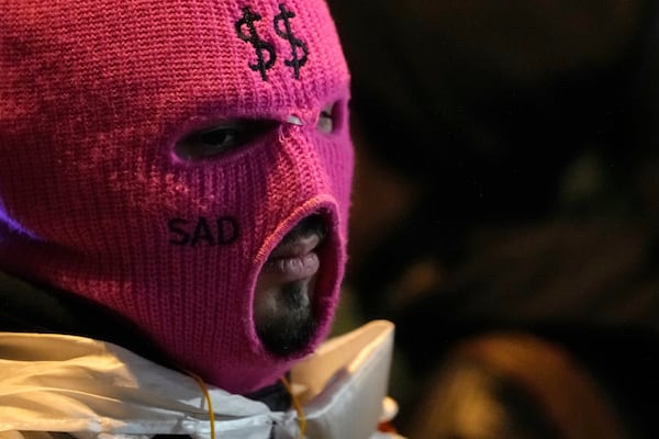 A demonstrator wearing a mask attends a rally outside the parliament building to protests against the government's decision to suspend negotiations on joining the European Union, in Tbilisi, Georgia, Wednesday, Dec. 4, 2024. (AP Photo/Pavel Bednyakov)