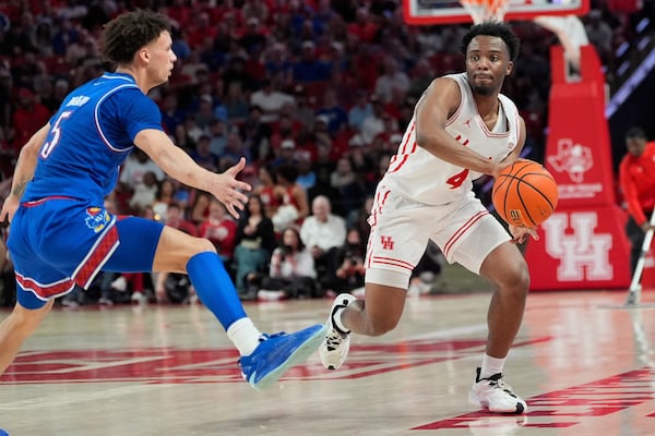 Houston's L.J. Cryer (4) passes the ball around Kansas' Zeke Mayo (5) during the second half of an NCAA college basketball game Monday, March 3, 2025, in Houston. (AP Photo/David J. Phillip)