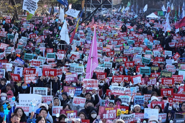 People hold signs before a rally to demand South Korean President Yoon Suk Yeol's impeachment outside the National Assembly in Seoul, South Korea, Saturday, Dec. 14, 2024. The letters read "Impeachment." (AP Photo/Lee Jin-man)