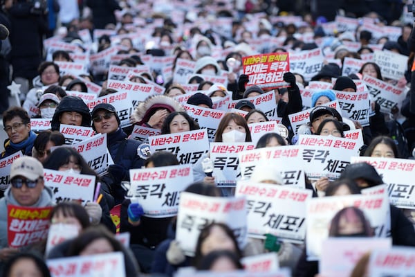 Participants shout slogans during a rally calling on the Constitutional Court to dismiss the President Yoon Suk Yeol in Seoul, South Korea, Sunday, Dec. 15, 2024. The signs read "Immediately arrest." (AP Photo/Lee Jin-man)