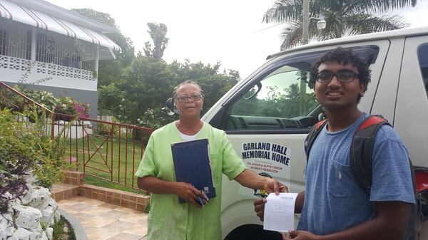 Fulton County high school student Amal Bhatnagar (right) with the director of the Garland Hall Memorial Hall, an orphanage for youths in Jamaica. There, he donated more than 100 first aid kits, thermometers, and pill containers to the orphans there. PHOTO CONTRIBUTED.