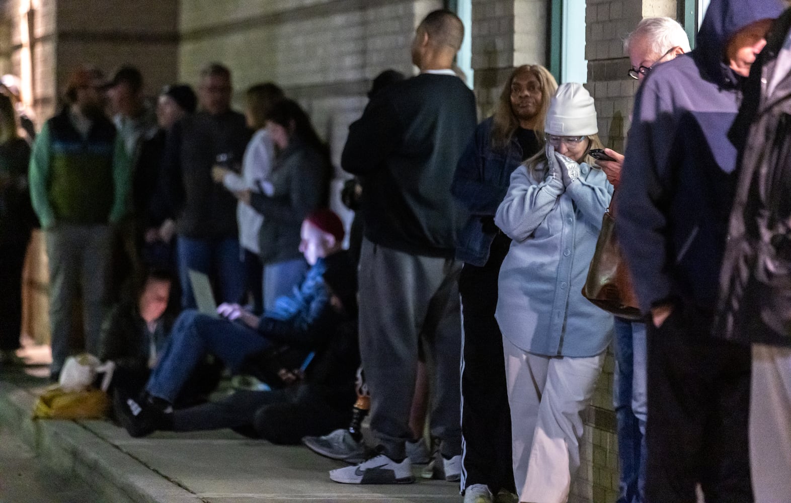 Jennifer Newlin (right) tries to stay warm along with fellow voters before the polls open at the Joan P. Garner Library located at 980 Ponce De Leon Ave N in Atlanta on Tuesday, Oct. 15, 2024. Polling places opened for the first day of early voting Tuesday as Georgia prepares for another tour as one of America’s most hotly contested states. The state’s 8.2 million registered voters will consider important races up and down the ballot. (John Spink/AJC)