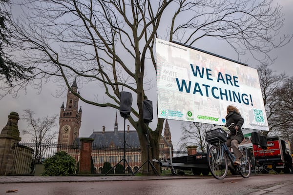 Activists protest outside the International Court of Justice, left, in The Hague, Netherlands, as it opens hearings into what countries worldwide are legally required to do to combat climate change and help vulnerable nations fight its devastating impact, Monday, Dec. 2, 2024. (AP Photo/Peter Dejong)