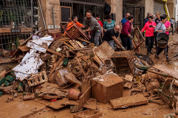 People clean mud from a shop affected by floods in Chiva, Spain, Friday, Nov. 1, 2024. (AP Photo/Manu Fernandez)