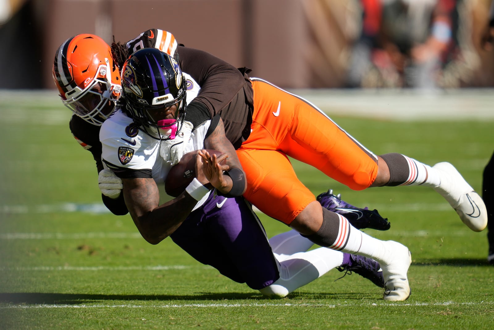 Baltimore Ravens quarterback Lamar Jackson (8) is tackled by Cleveland Browns defensive end Isaiah McGuire (57) during the first half of an NFL football game in Cleveland, Sunday, Oct. 27, 2024. (AP Photo/Sue Ogrocki)