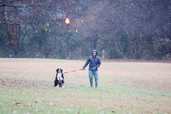 A person plays with his dog during light snow over Piedmont Park onover Piedmont Park on Sunday, January 16, 2022. The Georgia Department of Transportation advise motorists to stay off the roads as snow falls in parts of metro Atlanta Sunday morning. Miguel Martinez for The Atlanta Journal-Constitution 