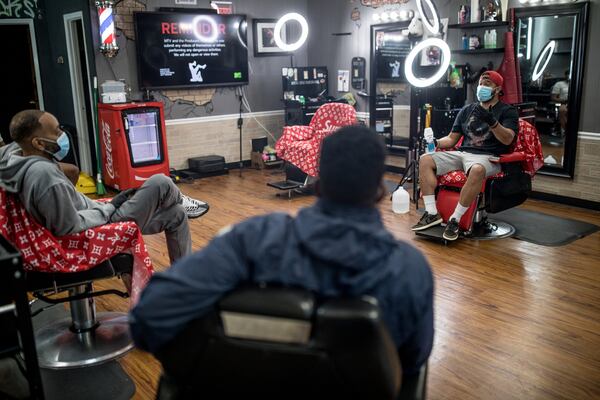 Blessed Up Barbershop Owner Taurean Overall, right, goes over safety measures to help prevent the spread of Coronavirus when they open back up on Friday on Wednesday, April 22, 2020, in Marietta, Ga.   Blessed Up will also open up its Acworth and Canton locations after Gov. Kemp is allowing certain businesses reopen for business.  BRANDEN CAMP/SPECIAL