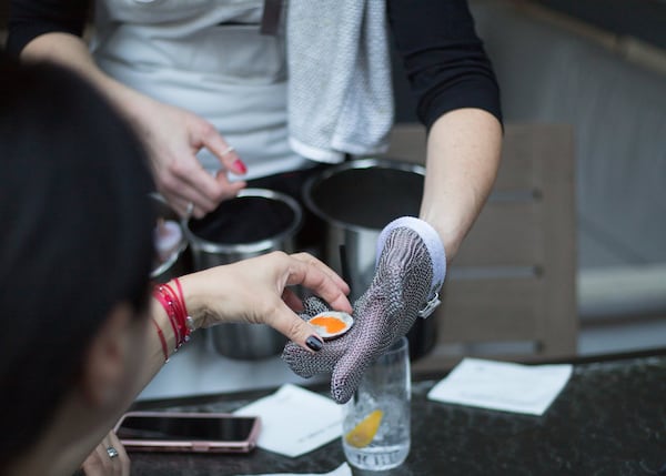 An Oysters Co server adds mignonette sauce to a freshly shucked oyster. PHOTO CREDIT: KayteeRuth Photography