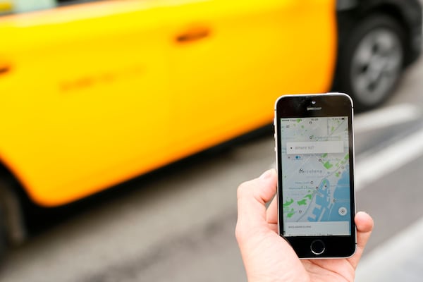 Filing taxes can be more complex for those who work in the gig economy, such as driving for Uber or Lyft. A taxi drives by a phone displaying the Uber app in Barcelona on March 13, 2018.