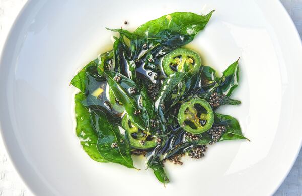 Detail of oil (or ghee) infused with dried chiles, black mustard seeds, coconut and curry leaves, a mixture that was put on top of the Khaman Cornbread. (Styling by chef Farhan Momin / Chris Hunt for the AJC)