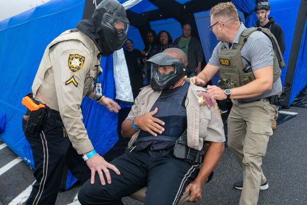 Gwinnett County law enforcement conducts an active drill exercise at the Gwinnett County Courthouse on Saturday, Dec 2, 2023 coordinating five law enforcement departments.  Officer J. Hodges, center, is evacuated from the courthouse after being shot twice during the exercise.  Hospital tents are set up and people are organized based on their injuries.  (Jenni Girtman for The Atlanta Journal-Constitution)