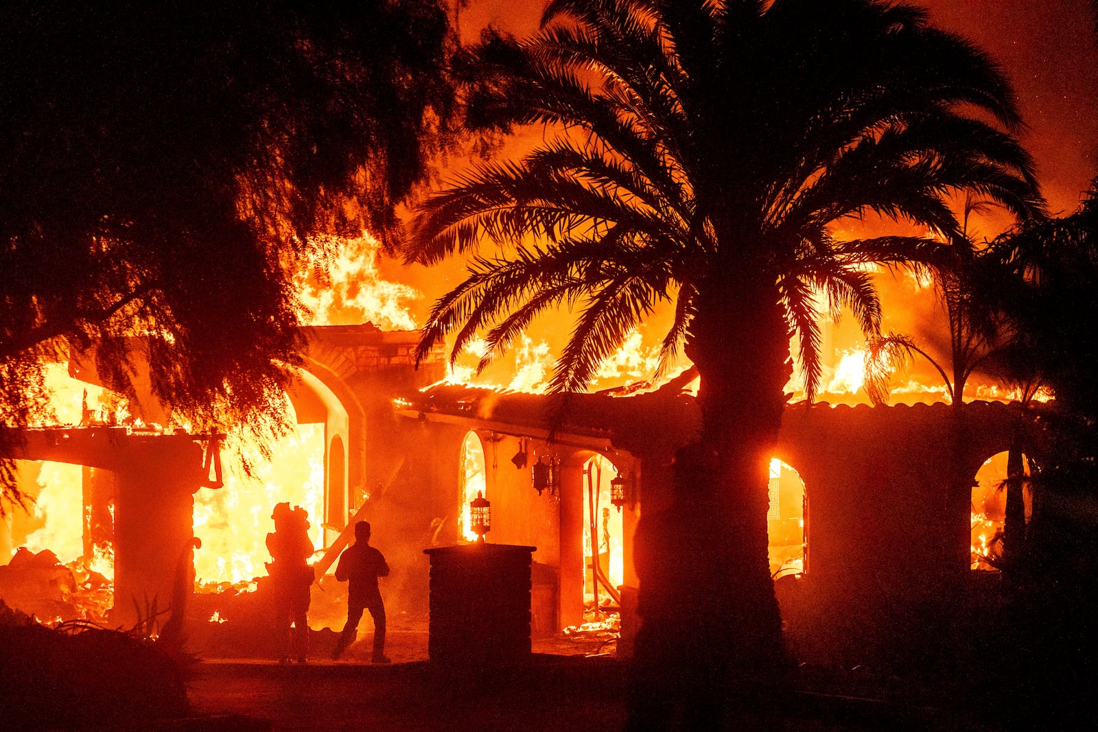 Television reporters film as flames from the Mountain Fire consume a home in Camarillo, Calif., on Wednesday, Nov. 6, 2024. (AP Photo/Noah Berger)