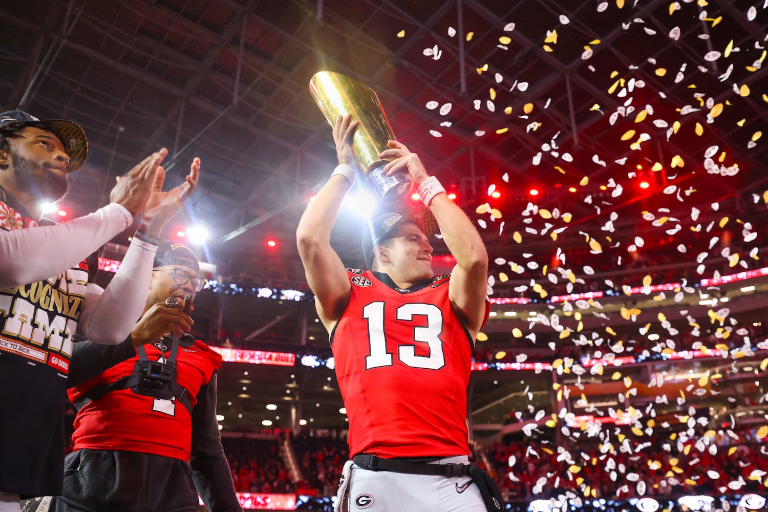 Georgia Bulldogs quarterback and offensive most valuable player Stetson Bennett (13) celebrates with the trophy after defeating the TCU Horned Frogs 65-7 in the College Football Playoff National Championship at SoFi Stadium in Los Angeles on Monday, January 9, 2023 to secure a second consecutive national title. (Jason Getz / Jason.Getz@ajc.com)