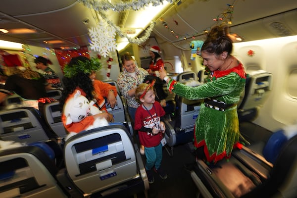 Flight attendant Dre Zulaica, right, of San Francisco, greets 7-year-old Greyson Thomas, of Denver, during the United Airlines annual "fantasy flight" to a fictional North Pole at Denver International Airport, Saturday, Dec. 14, 2024, in Denver. (AP Photo/David Zalubowski)