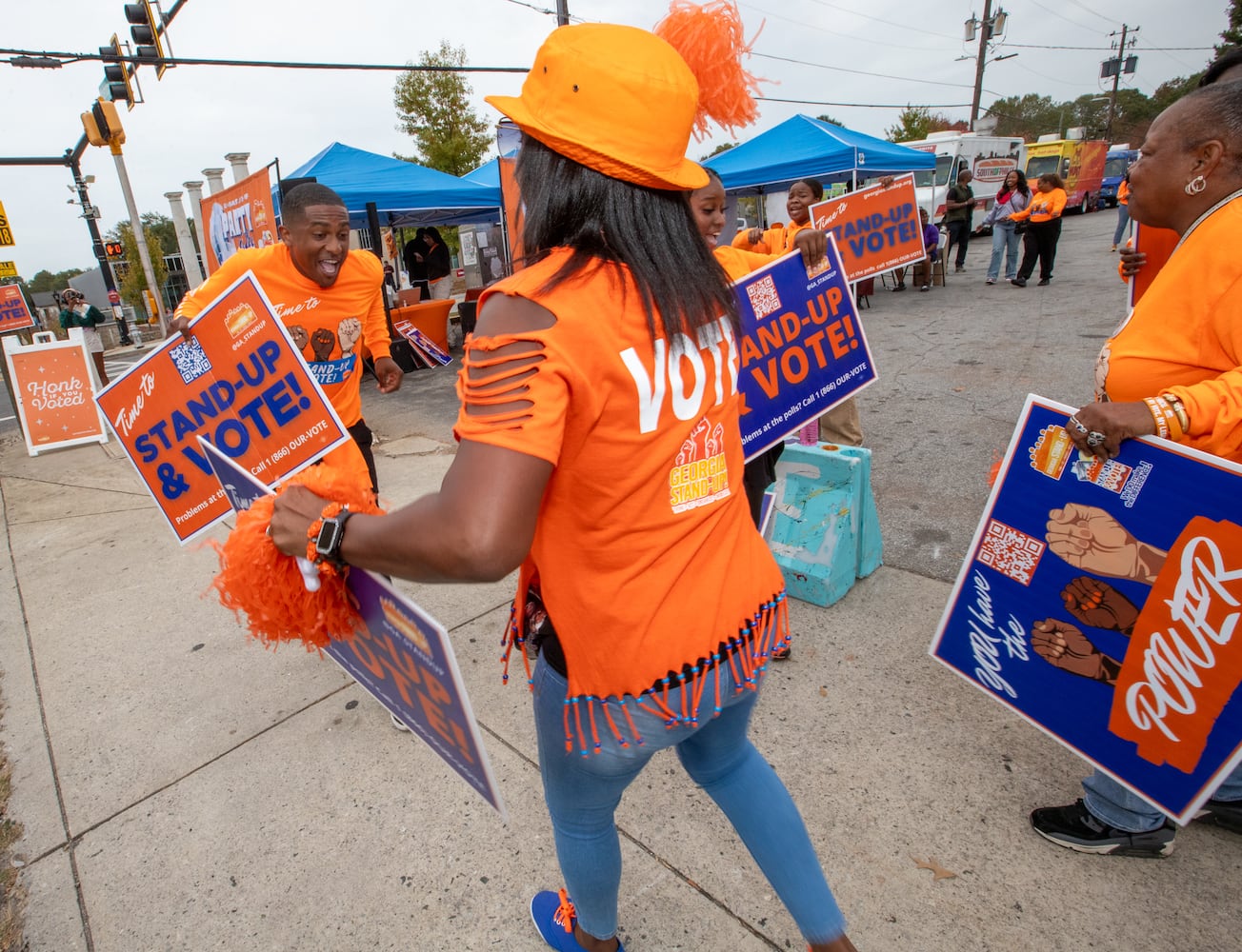 The last day of early voting in Georgia takes place at Metropolitan Library in South Fulton County; across the street several non-profit, non-partisan groups, including Rubin Barksdale, left, and Regina Gibbs, volunteers with Georgia Stand Up, dance and cheer, provided free food, information and swag to encourage people to vote Friday, November 1, 2024.  The polling location had a steady stream of voters throughout the day.  (Jenni Girtman for The Atlanta Journal-Constitution)