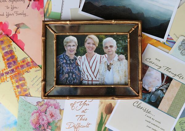 An October 2019 family photo of (from left) Clarissa Strickland, her daughter Courtenay Strickland, and her sister Nan Durrett is seen with sympathy cards. Nan Durrett, 74, died last month after becoming ill in an assisted living home. Her family believes the state needs to set higher care standards for the senior care industry. (Curtis Compton /ccompton@ajc.com)