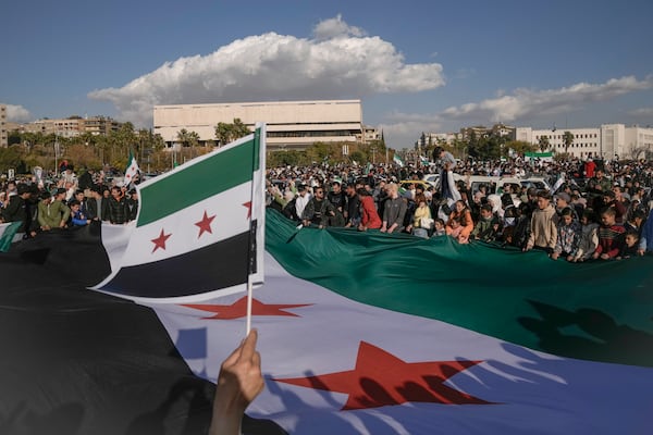 Syrians display a giant "revolutionary" Syrian flag during a celebratory demonstration following the first Friday prayers since Bashar Assad's ouster, in Damascus' central square, Syria, Friday, Dec. 13, 2024. (AP Photo/Leo Correa)