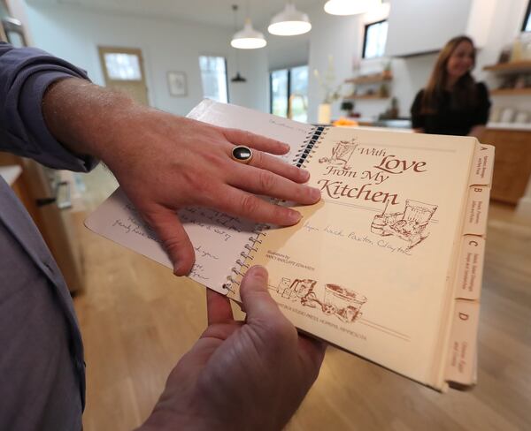 Matt Paxton, a former expert on “Hoarders,” shows off two of his personal legacy items, the family cookbook of his mother Lynn Clayton and the Tiffany’s gold ring of his father Ed Paxton. Curtis Compton / Curtis.Compton@ajc.com