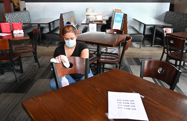 April 25, 2020 Decatur - Leah Johnson, employee, uses a disinfectant wipe to sanitize chairs as they prepare to reopen the restaurant at Bad Daddy's Burger Bar in Decatur on Saturday, April 25, 2020. On Monday, Kemp announced shuttered businesses including barbershops, beauty and nail salons, spas, gyms and bowling alleys could reopen Friday. Movie theaters and restaurant dining rooms can reopen Monday. (Hyosub Shin / Hyosub.Shin@ajc.com)